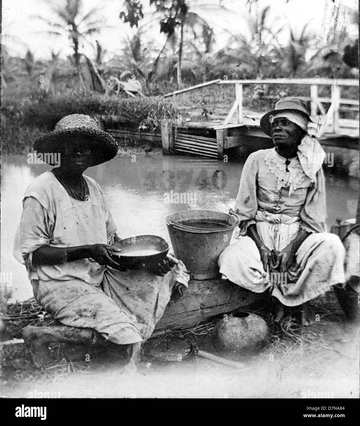 Zwei Frauen mit Eimern am Ufer sitzen Stockfoto