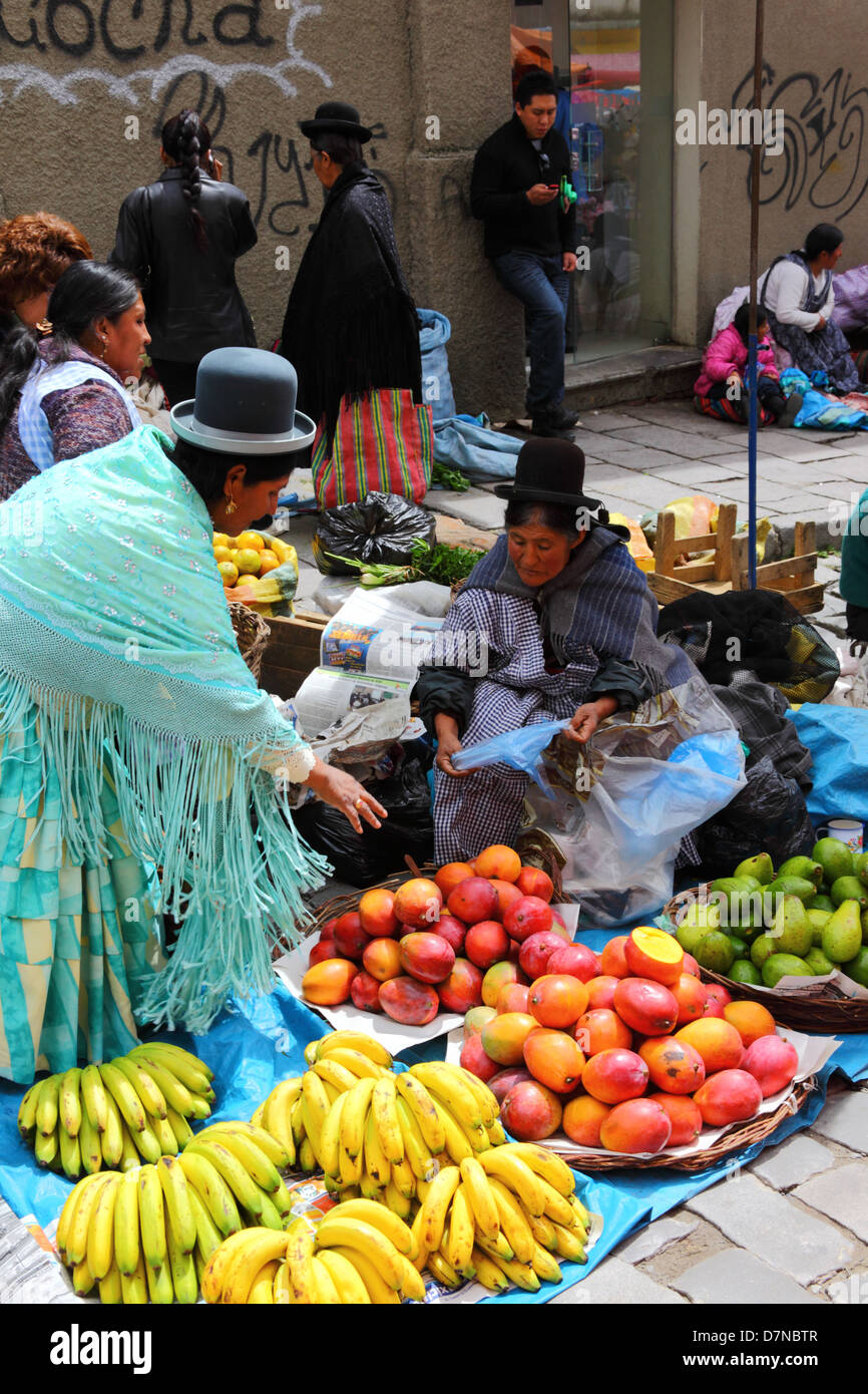 Aymara Dame oder Cholita kauft Obst im Mercado Rodriguez, einem typischen Straßenmarkt in der Nähe des Stadtzentrums La Paz, Bolivien Stockfoto