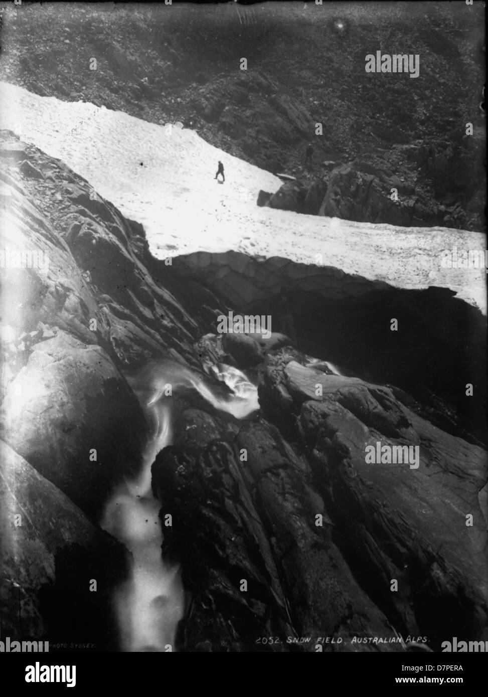 Dieses Foto von Charles H. Kerry fängt die schneebedeckten Felder der australischen Alpen ein. Das Bild zeigt die krasse Schönheit der alpinen Landschaft, mit dunklen Felsen, die sich von Schnee und Eis abheben, in einer atemberaubenden, winterlichen Szene. Stockfoto