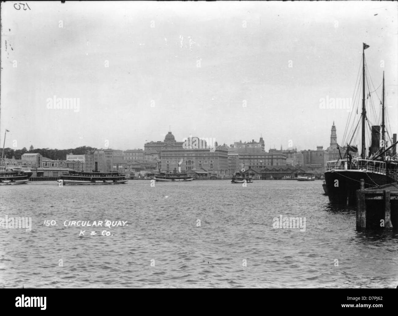 Ein historischer Blick auf den Circular Quay in Sydney, aus dem Südosten, mit Blick auf den belebten Hafen und die umliegende Stadtlandschaft. Dieses Foto zeigt die ikonische Umgebung einer der geschäftigsten Gegenden Sydneys, bekannt für seine maritime und Transportgeschichte. Stockfoto