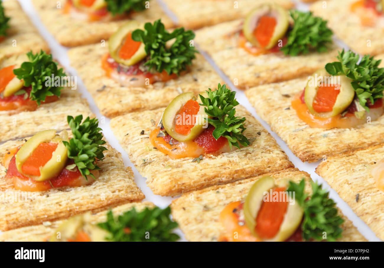 Snacker Cracker - Weizen Cracker belegt mit Käse, Oliven, Petersilie und Sauce gebacken. Stockfoto