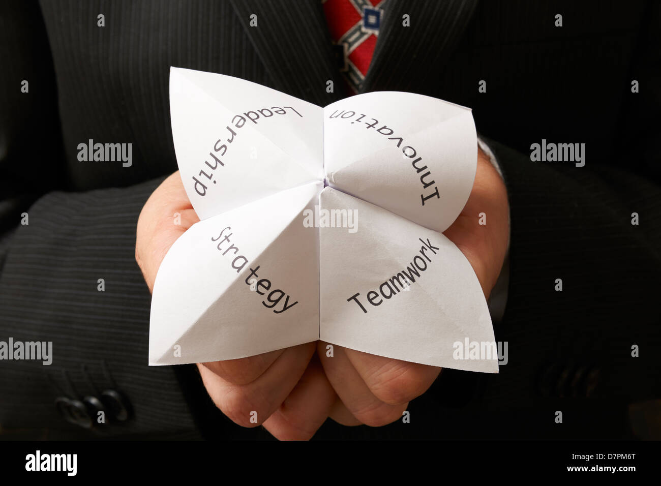 Business-Mann hält Origami Wahrsagerin mit Teamarbeit, Führung, Innovation und Strategie, die darauf geschrieben Stockfoto
