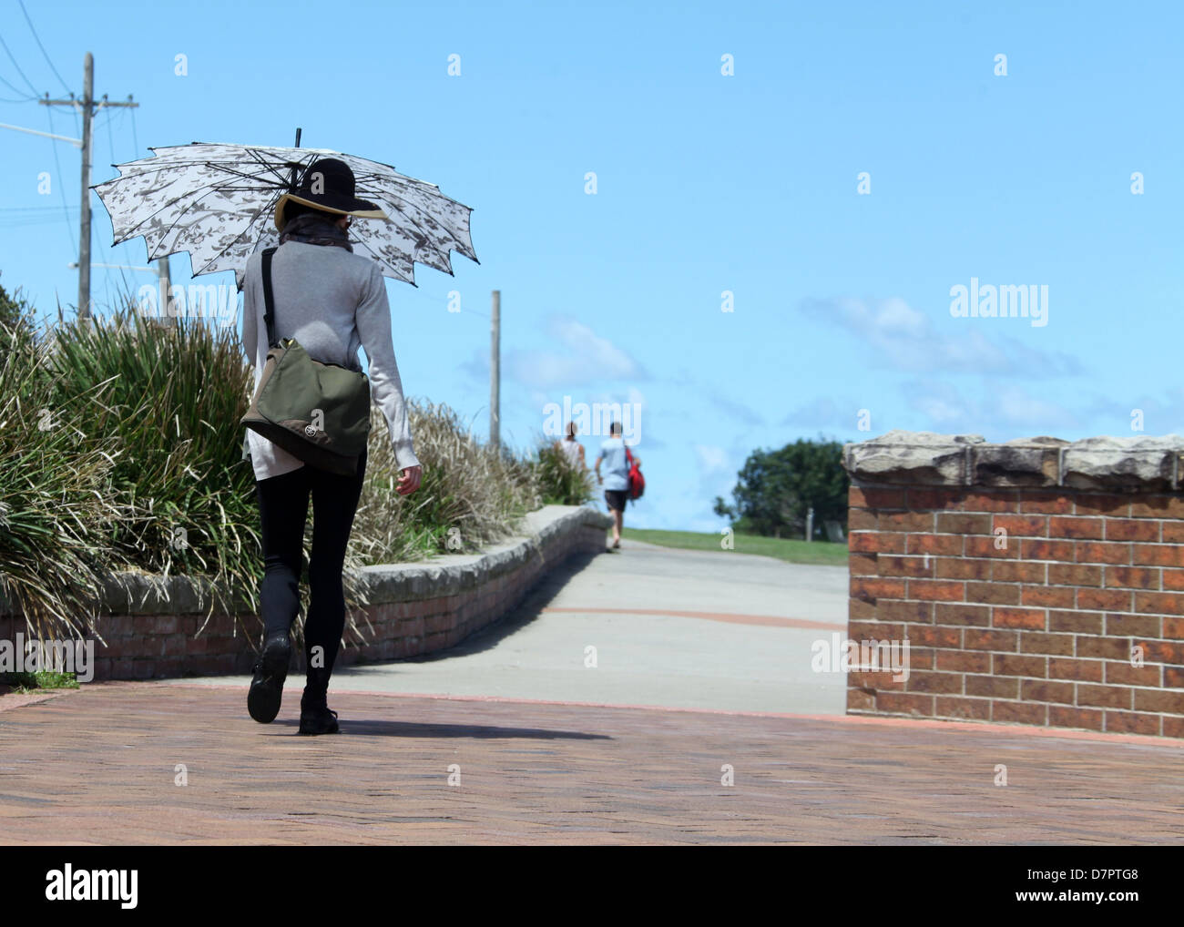 Frau zu Fuß mit einem Sonnenschirm auf der Bondi to Coogee Walk in Australien Stockfoto