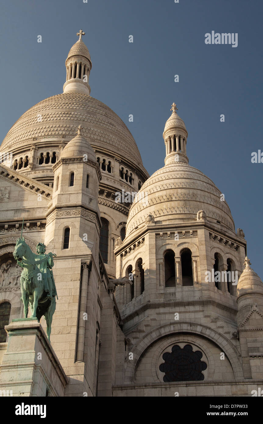 Die hoch aufragenden weißen Kuppeln der Basilika Sacré-Coeur auf dem Montmartre. Über dem Portikus steht ein Reiterstandbild der Jeanne d ' Arc. Paris, Frankreich. Stockfoto