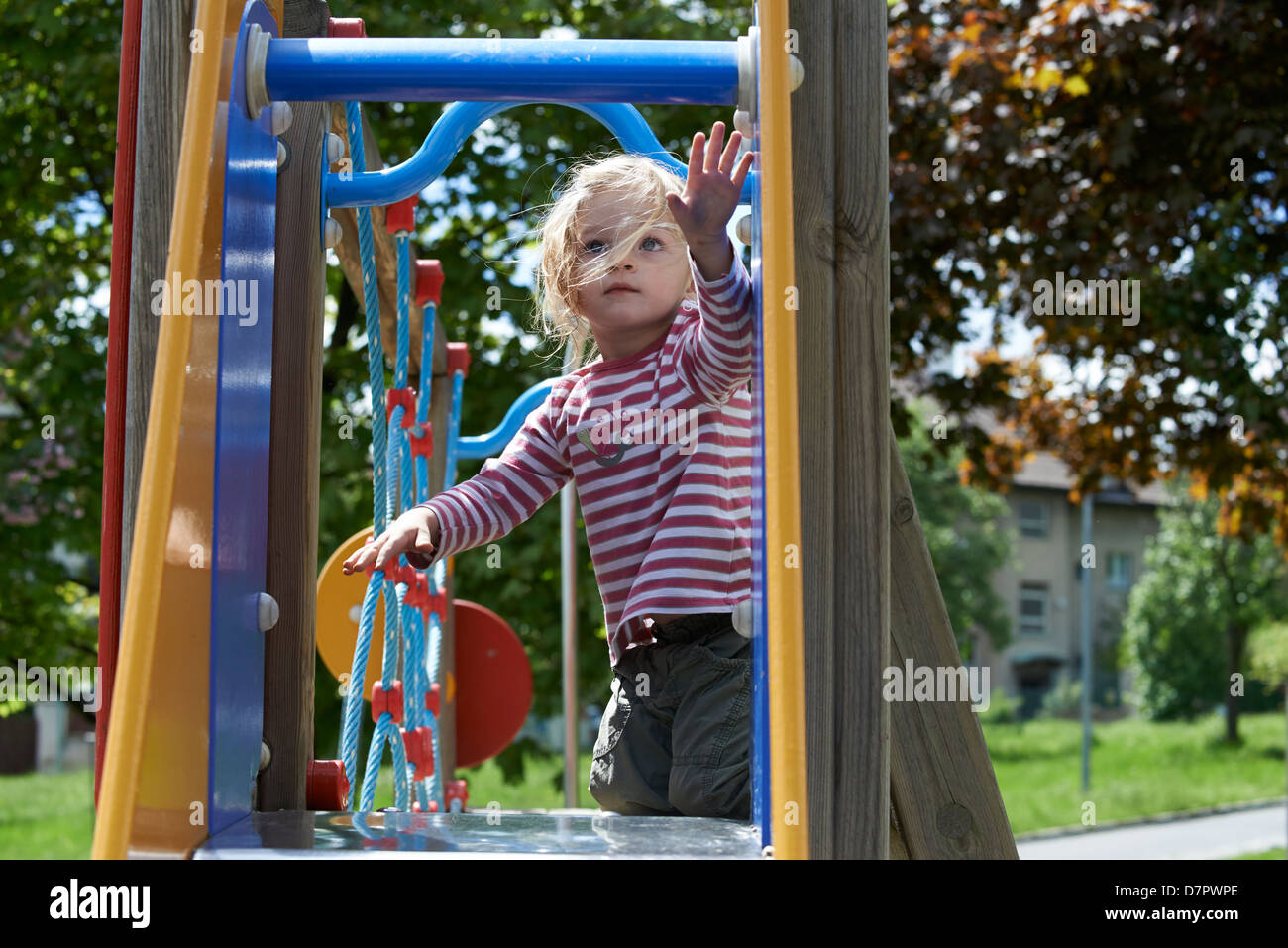 Blonde Mädchen Kind gleitende Folie auf einem Spielplatz Stockfoto