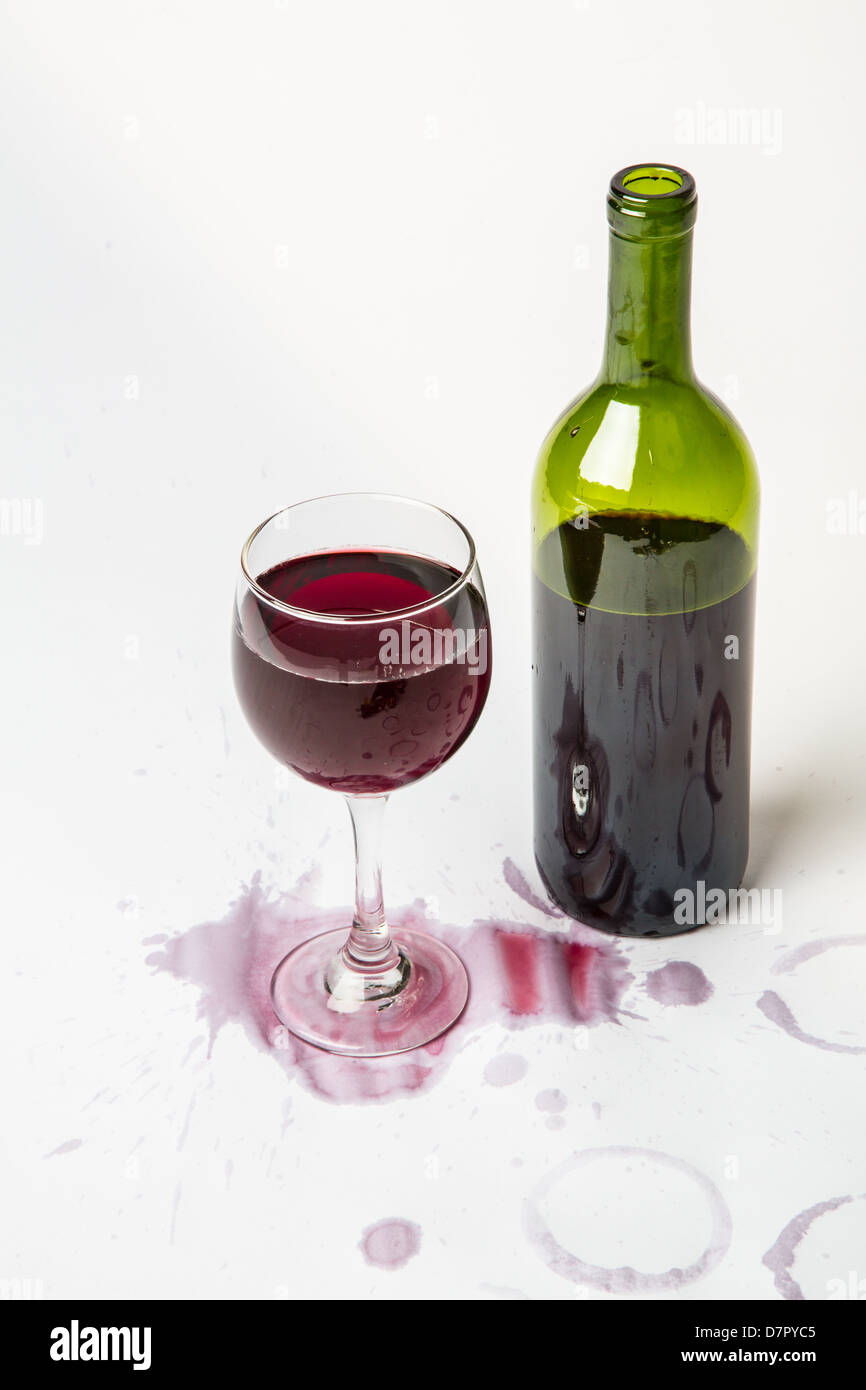 Ein volles Glas Rotwein mit der Flasche und verschmutzten weißen Hintergrund. Stockfoto