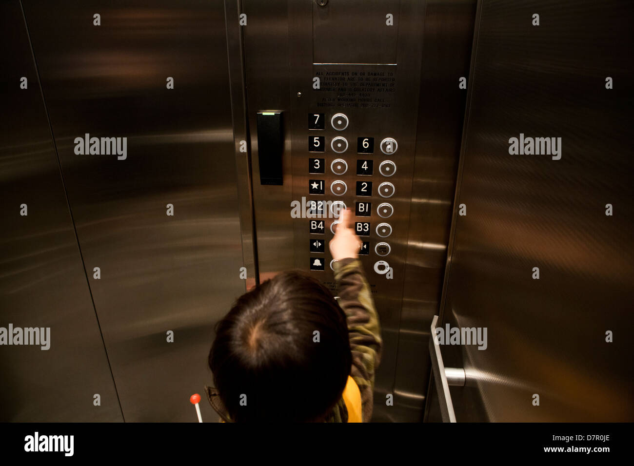 Kind im Aufzug Etage drücken - USA Stockfoto