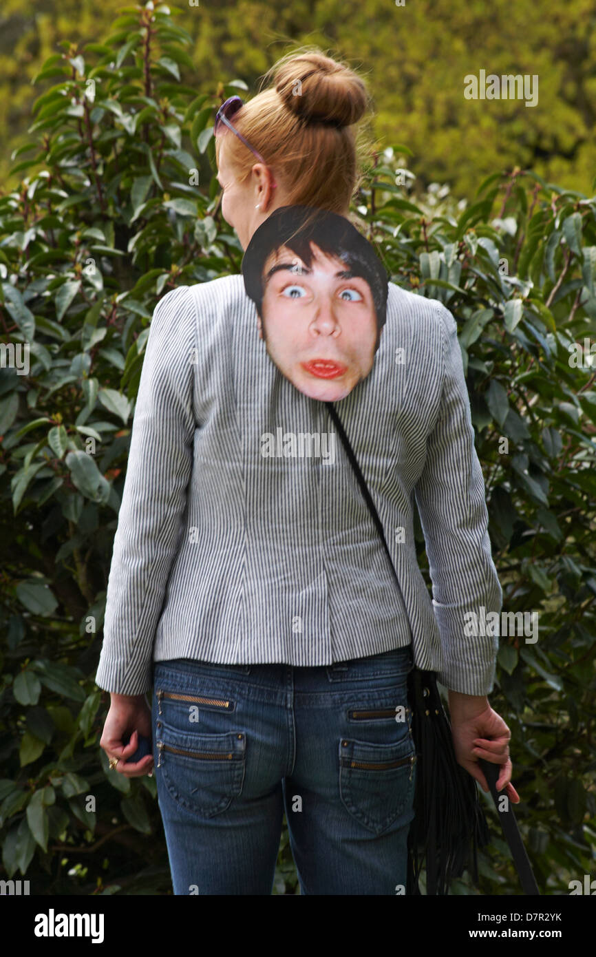 Frau mit Gesichtsmaske, die im April in Bath, Somerset UK, um ihren Rücken hängt Stockfoto