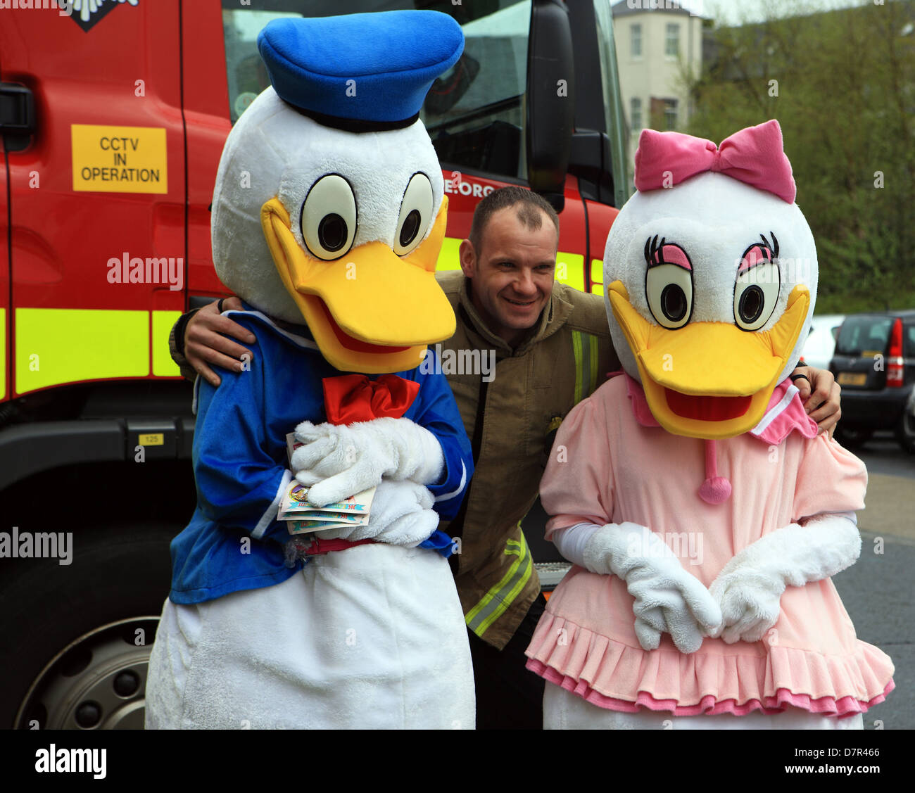 Donald und Daisy Duck posiert mit einem Feuerwehrmann bei der jährlichen Entenrennen der Paisley in Schottland Stockfoto