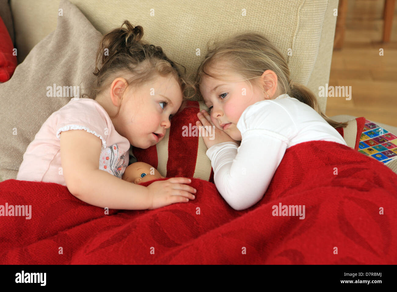Jüngere Schwester Sorge gegenüber ihrer älteren Schwester, die ist nicht gut und liegt auf der Couch mit einem Wurf zeigen, über Sie Stockfoto