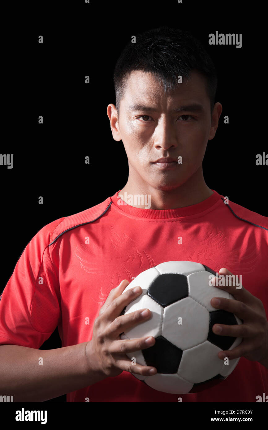 Fußballspieler mit Ball, Brust, schwarzer Hintergrund Stockfoto