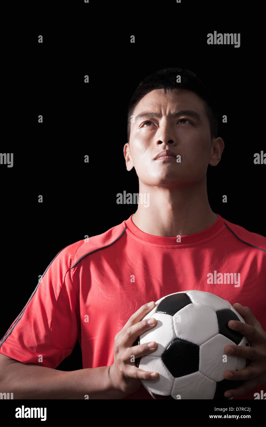 Fußballspieler mit Ball, Brust, schwarzer Hintergrund Stockfoto