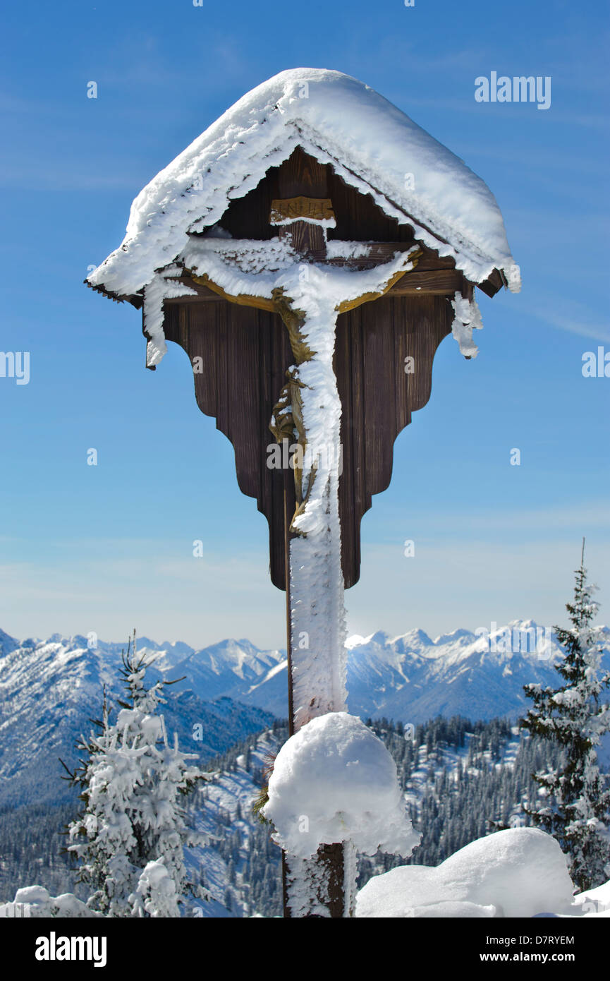 Holzkreuz mit Eis und Schnee auf den Bergen in Bayern Stockfoto