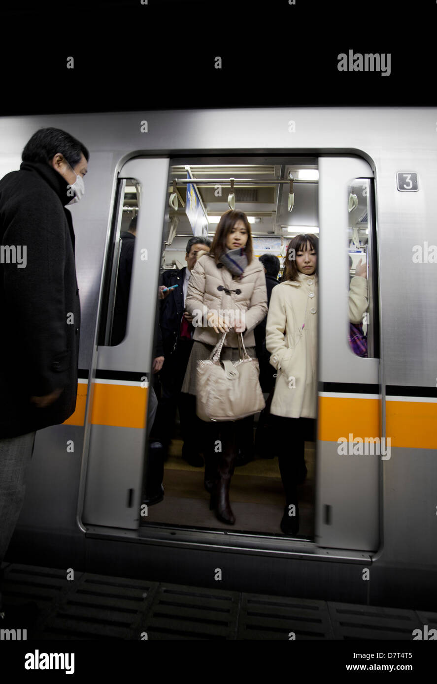 Pendler verlassen einen Zug auf der Tokyo Metro mit Mann wartet an Bord Stockfoto