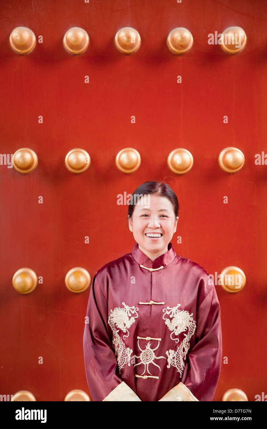 Reife Frau in traditioneller Kleidung stehen neben traditionellen chinesischen Tür Stockfoto