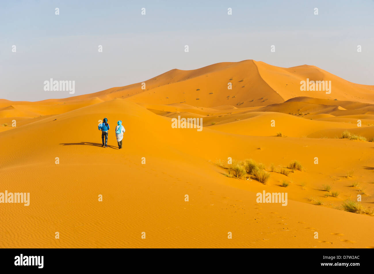 Zwei Berber Männer gehen in den Sanddünen des Erg Chebbi Wüste Sahara in der Nähe von Merzouga, Marokko, Nordafrika Stockfoto