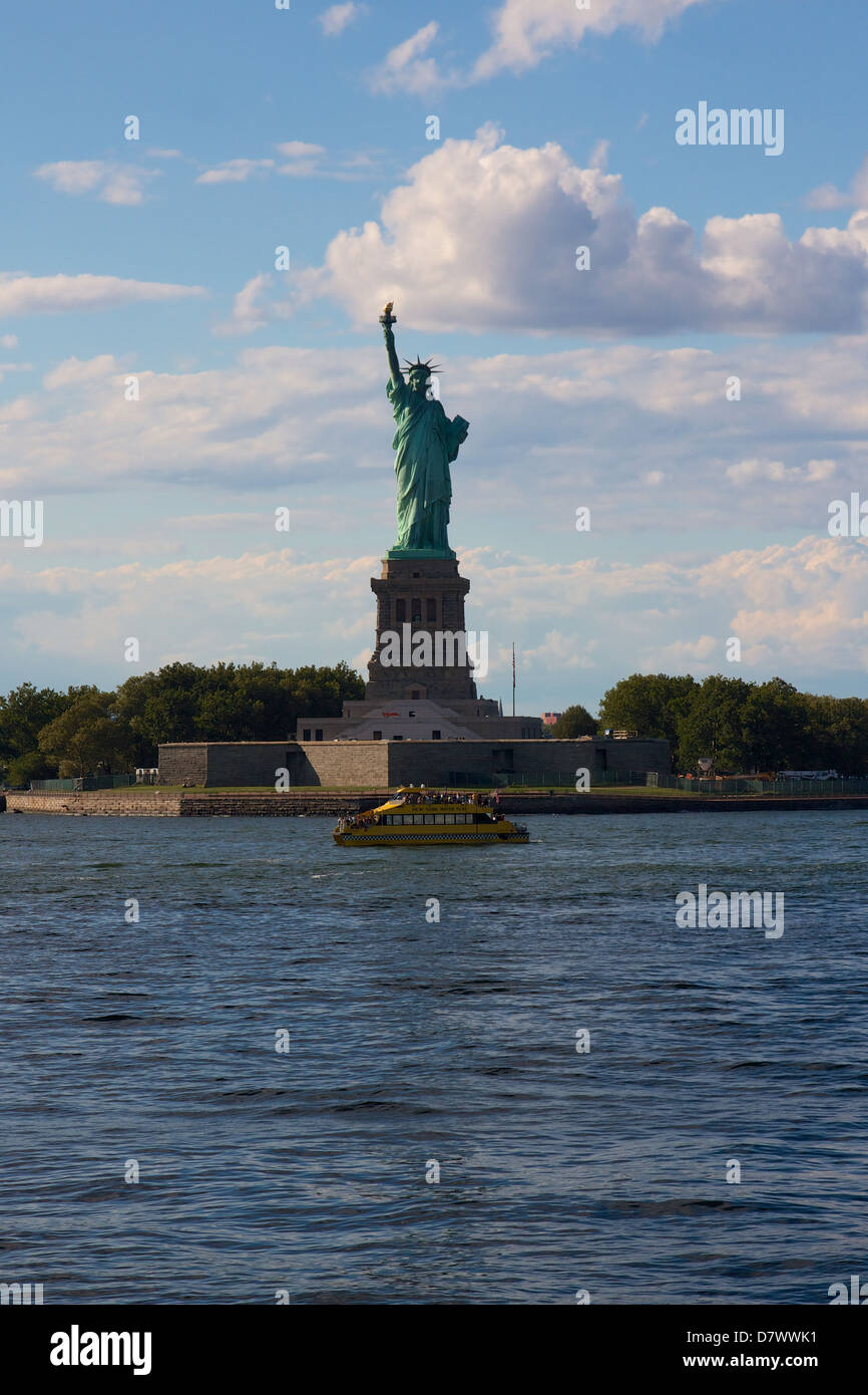 Die Freiheitsstatue auf Liberty Island, New York, NY, USA, mit einer NYC Wassertaxi von davon übergeben. Stockfoto