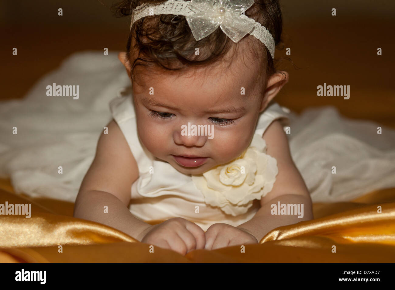Babymädchen mit auf Bett wunderschön gekleidet in einem weißen Taufe Kleid für ihre Taufe Stockfoto