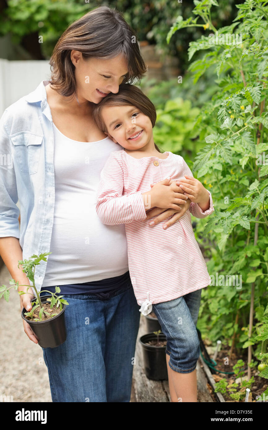 Schwangere Mutter und Tochter zusammen im Garten Stockfoto