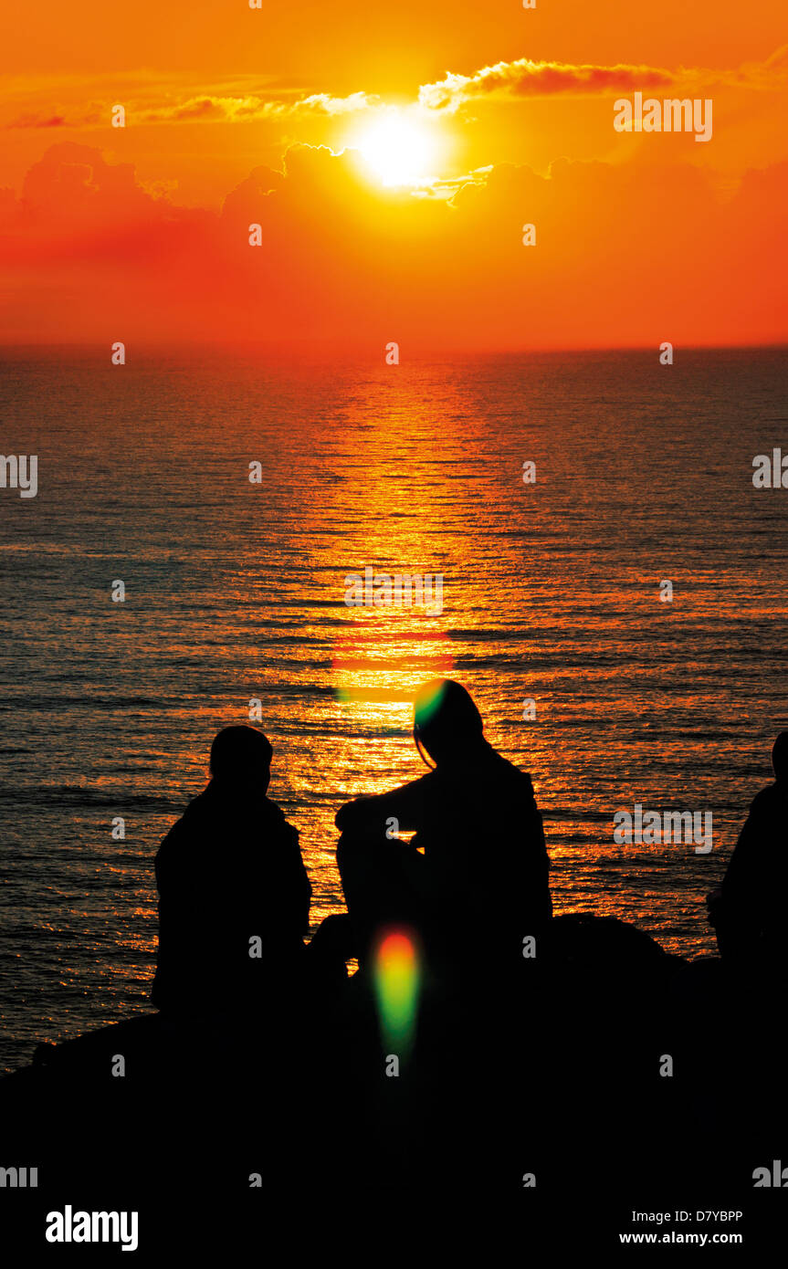 Spanien, Jakobsweg: St. James Pilger sitzen an den Klippen von Kap Fisterra beobachten den Sonnenuntergang Stockfoto