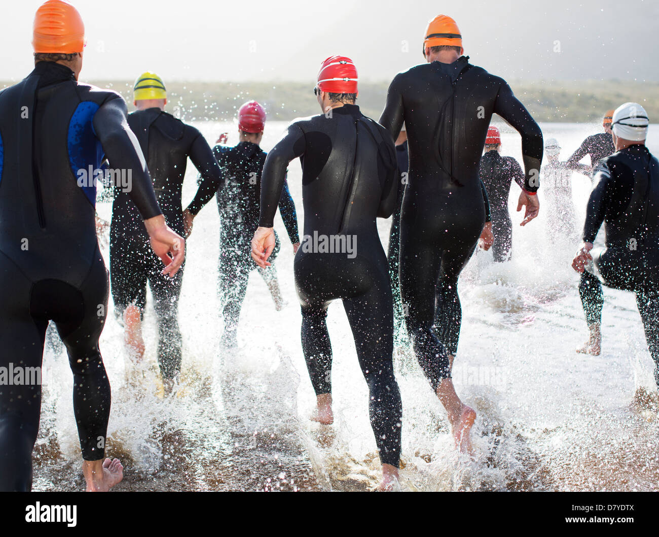 Triathleten in Neoprenanzüge in Wellen laufen Stockfoto