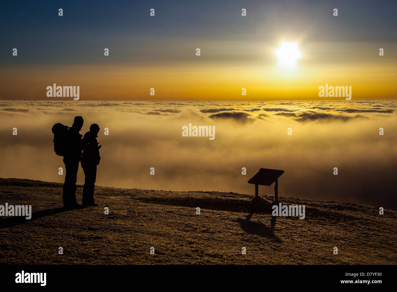 Zwei Wanderer auf einem Berg über den Wolken bei Sonnenuntergang Stockfoto