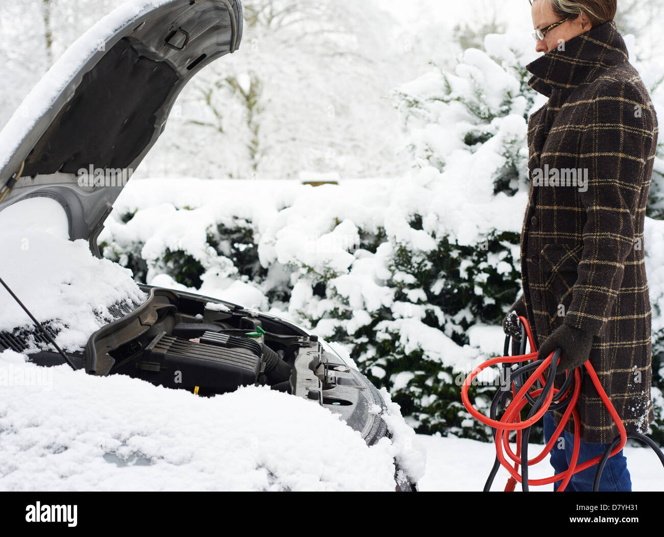 Frau arbeitet auf aufgeschlüsselt Auto im Schnee Stockfoto