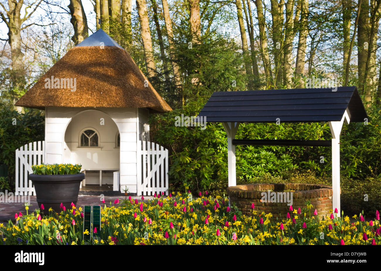 Ruhestätte und Brunnen mit Tulpen und Narzissen im Frühjahr im park Stockfoto