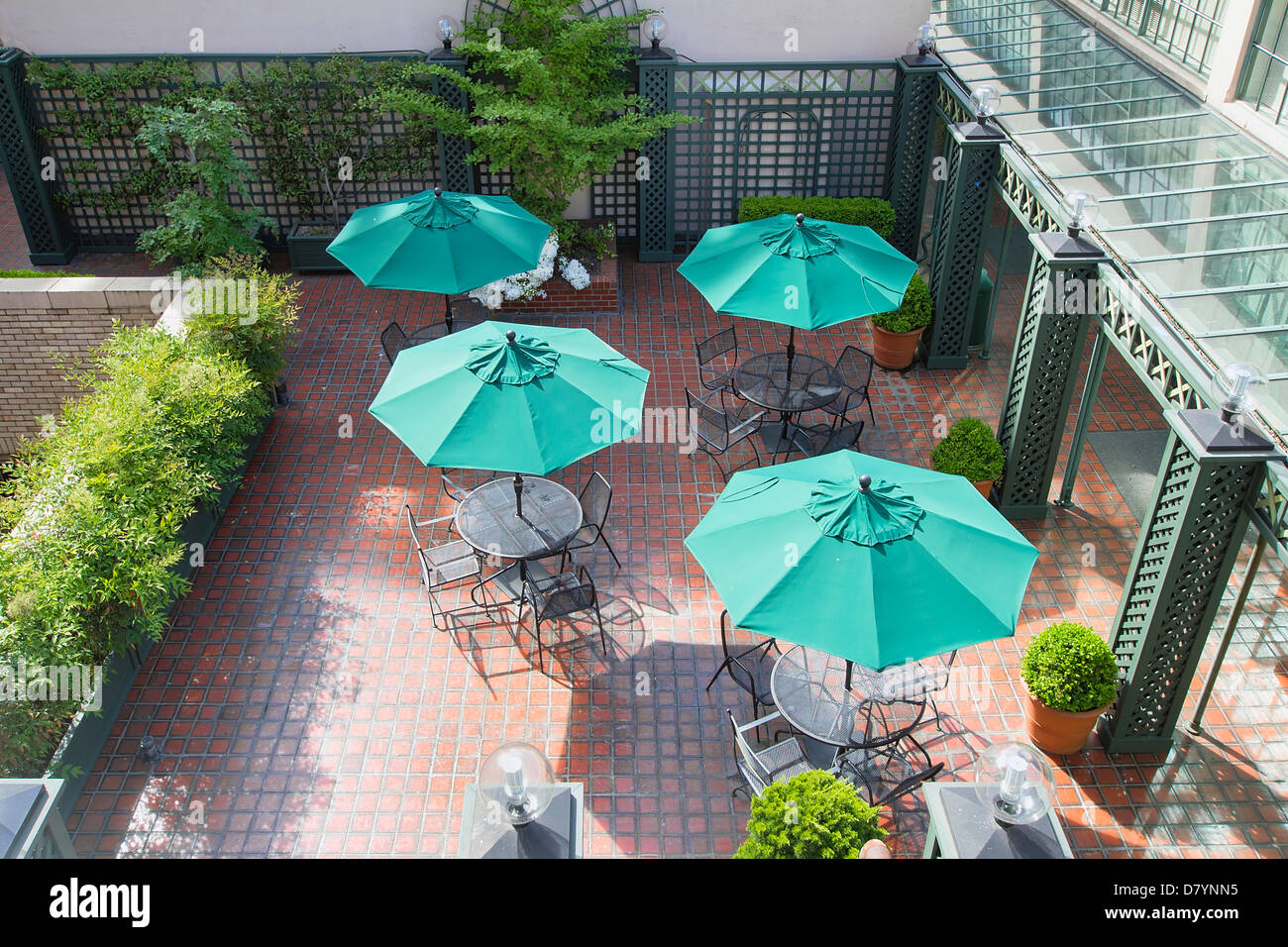 Terrasse Sitzgelegenheiten mit Tischen, Stühlen und grüne Schirme Stockfoto