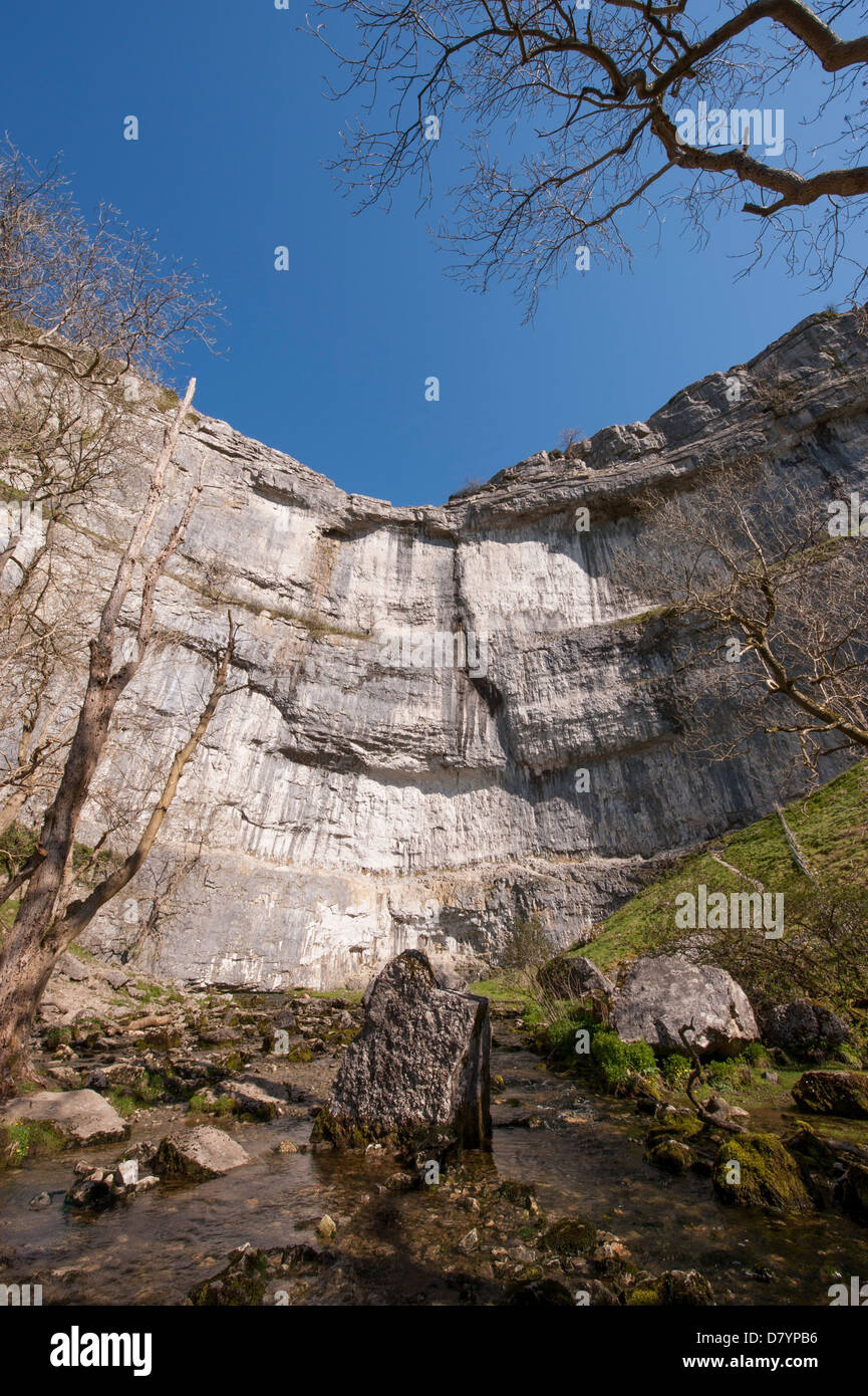 Sonnige Aussicht auf Wasser im Kessel von Malham Cove unter blauem Himmel - mit einem riesigen, steilen, gewundenen Kalksteinfelsen in wunderschönen Yorkshire Dales, England, GB, UK. Stockfoto