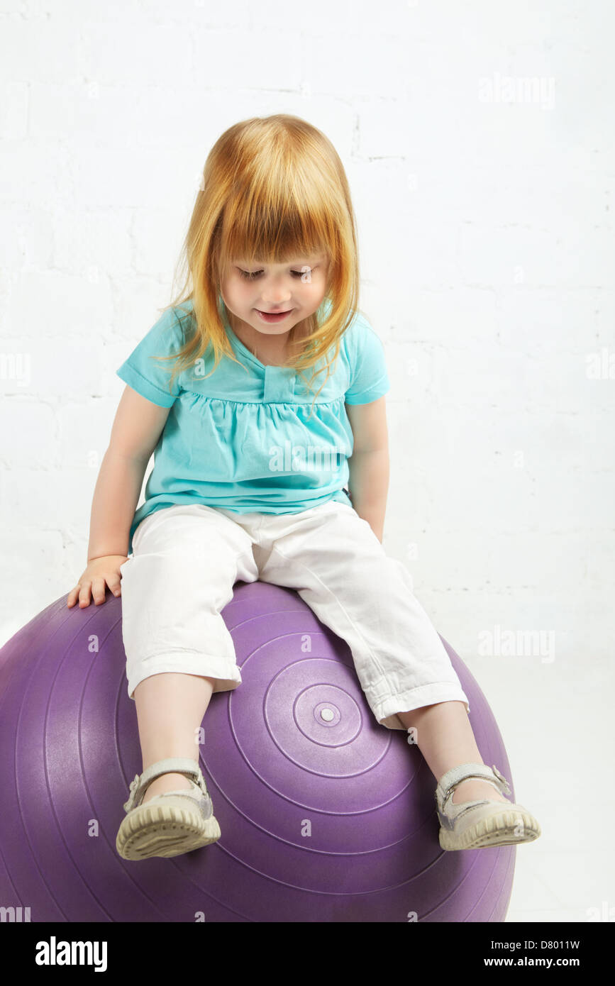 wunderschönes kleines Mädchen sitzen auf großen ball Stockfoto