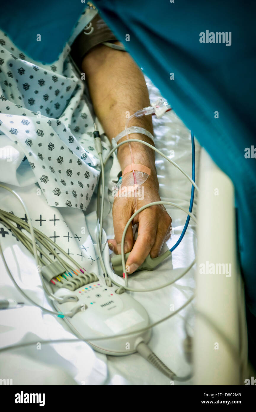 Ein Patient hat eine Infusion in den Arm eingefügt und ein Pulsoximeter, befestigt an den Finger, auf einer Intensivstation. Stockfoto