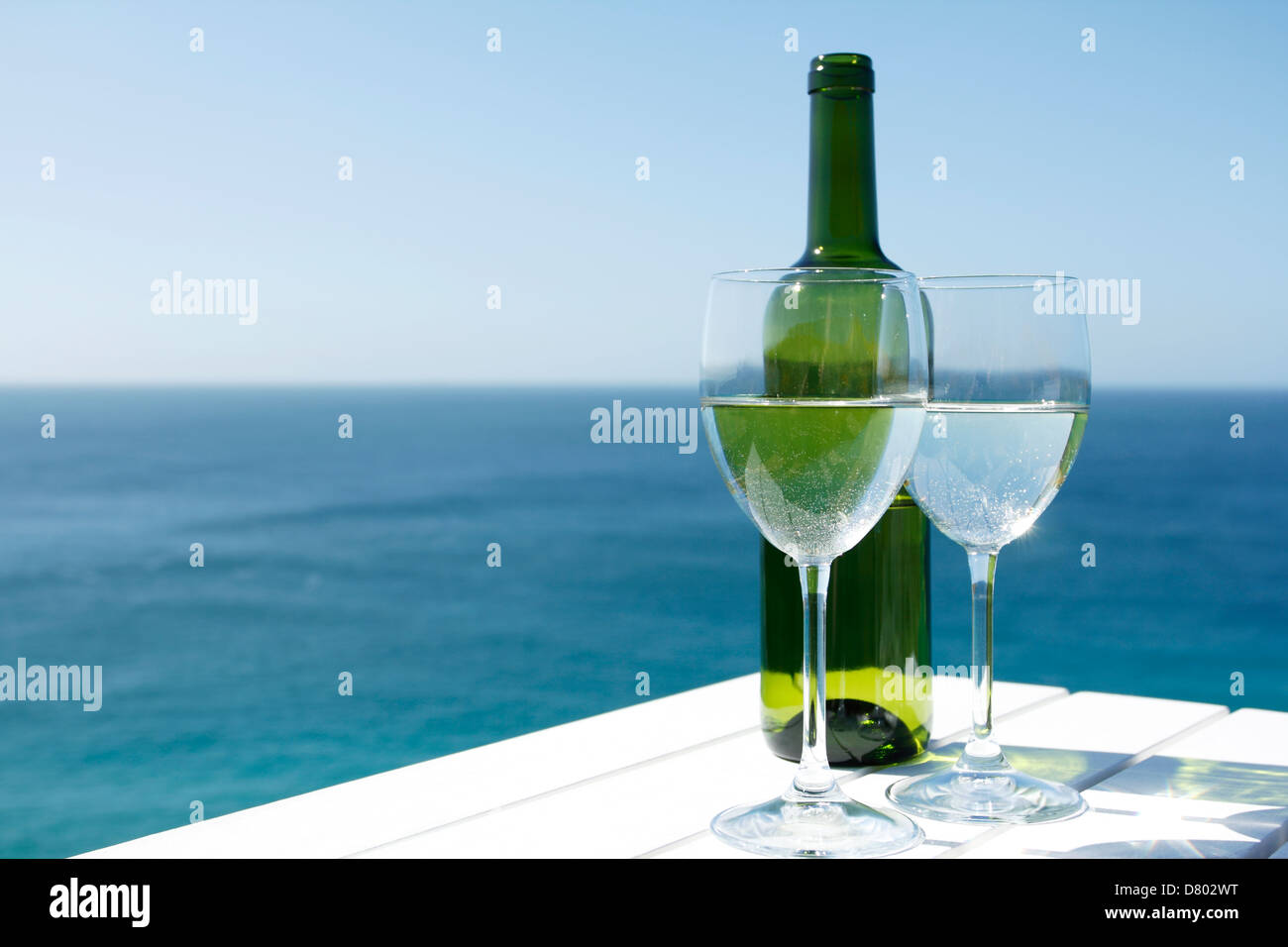 Gläser Wein auf einem weißen Tisch durch den Ozean. Stockfoto