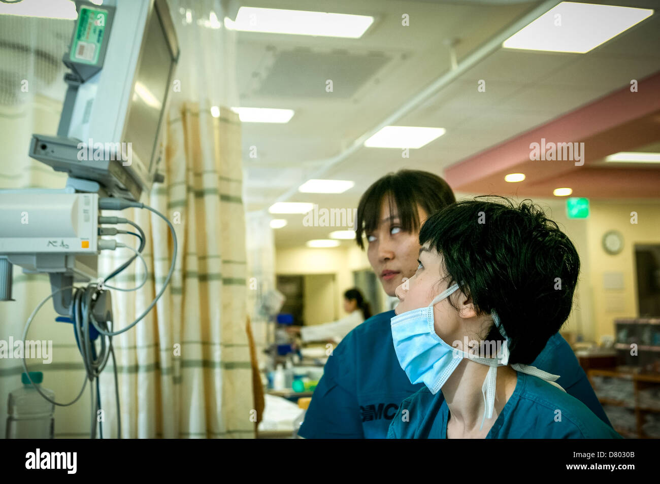 Zwei medizinische Personal aussehen auf den Monitor der Herzfrequenz Patienten auf der Intensivstation Krankenhaus. Stockfoto