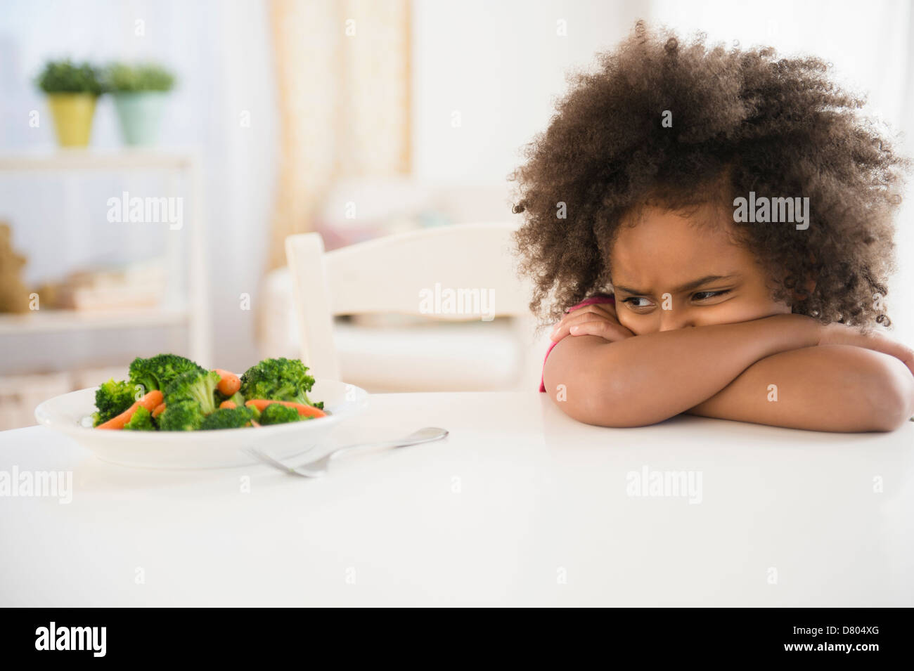 Afroamerikanische Mädchen weigert Gemüse am Tisch Stockfoto