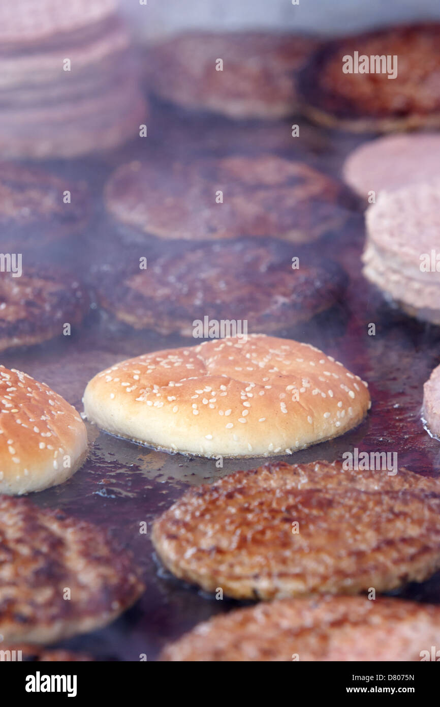 Roh und gekocht verarbeitet Hamburger auf einem kommerziellen flachen Grill auf ein outdoor-event Stockfoto