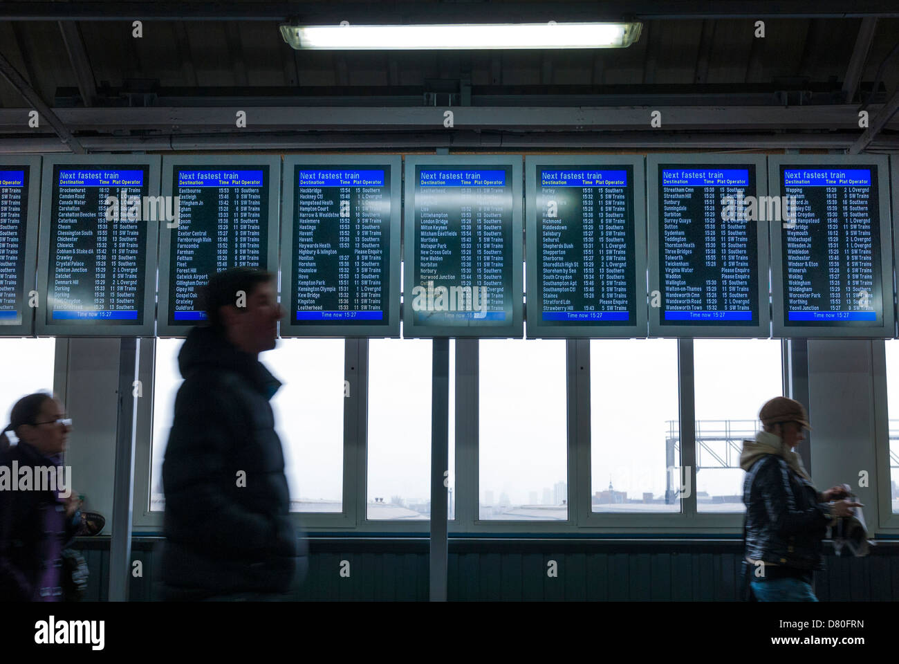 Passagiere, die zu Fuß durch elektronische Zuges anzeigen Board in Clapham Junction Stockfoto