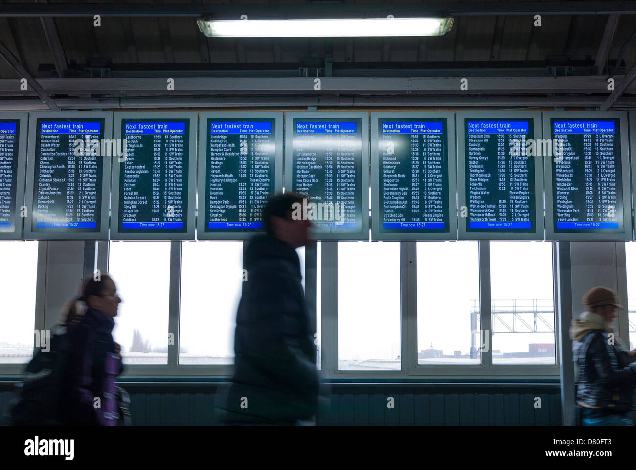 Passagiere, die zu Fuß durch elektronische Zuges anzeigen Board in Clapham Junction Stockfoto