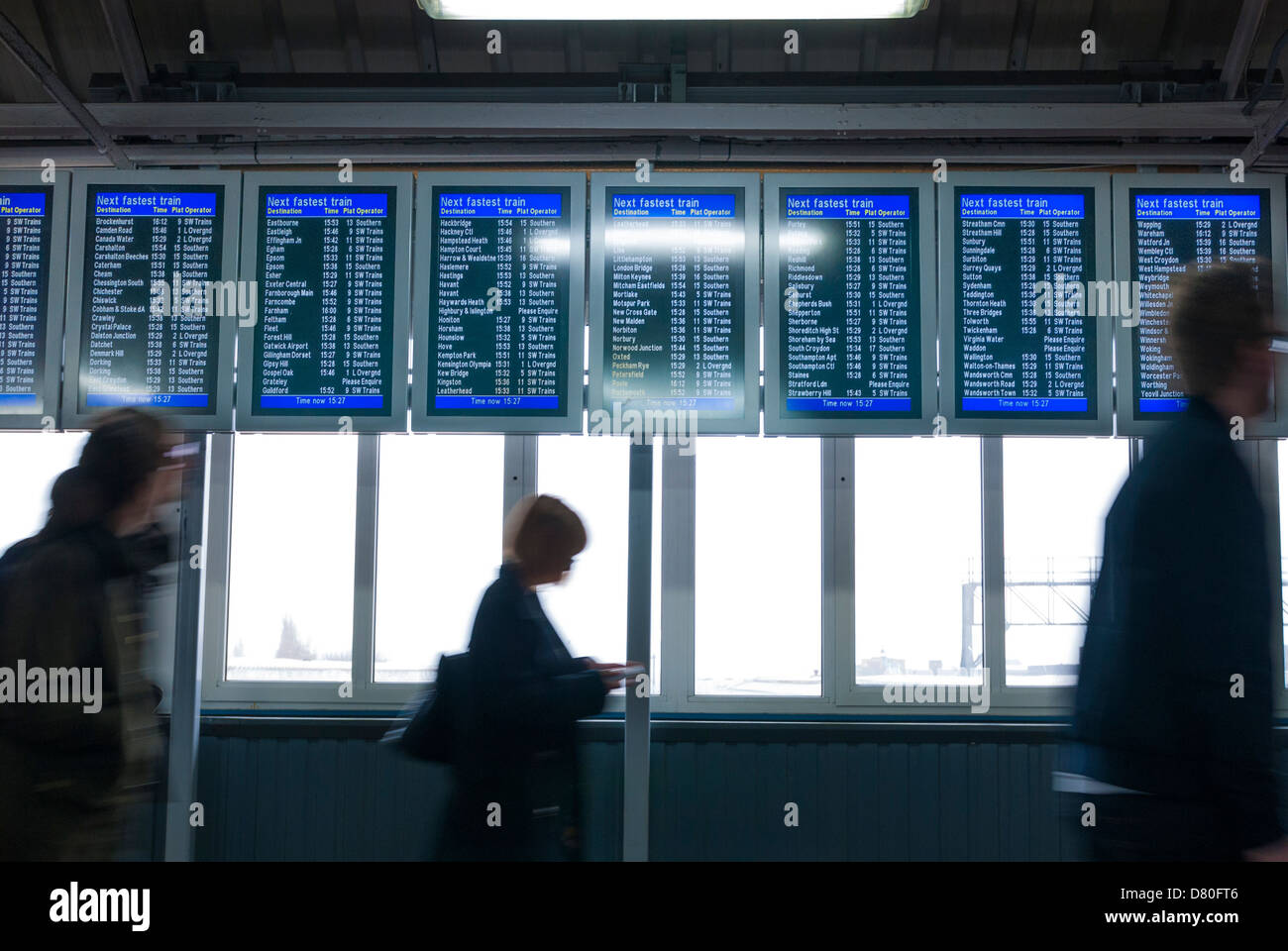 Passagiere, die zu Fuß durch elektronische Zuges anzeigen Board in Clapham Junction Stockfoto