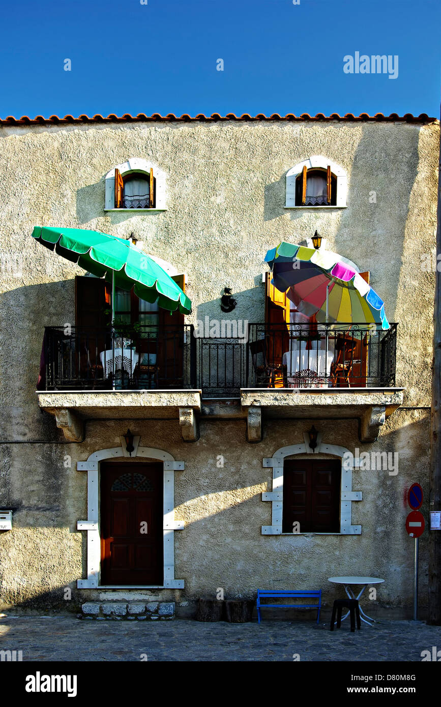 Typische mediterrane Steinhaus mit bunten Sonnenschirmen auf Balkonen an sonnigen Sommertag. Stockfoto