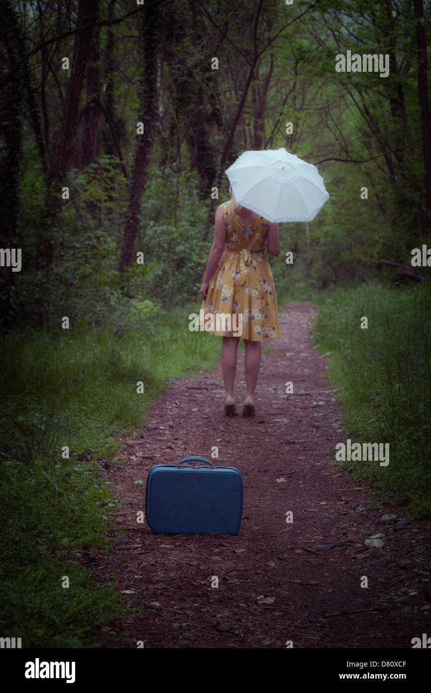 ein Mädchen mit Koffer und Regenschirm im Wald Stockfoto