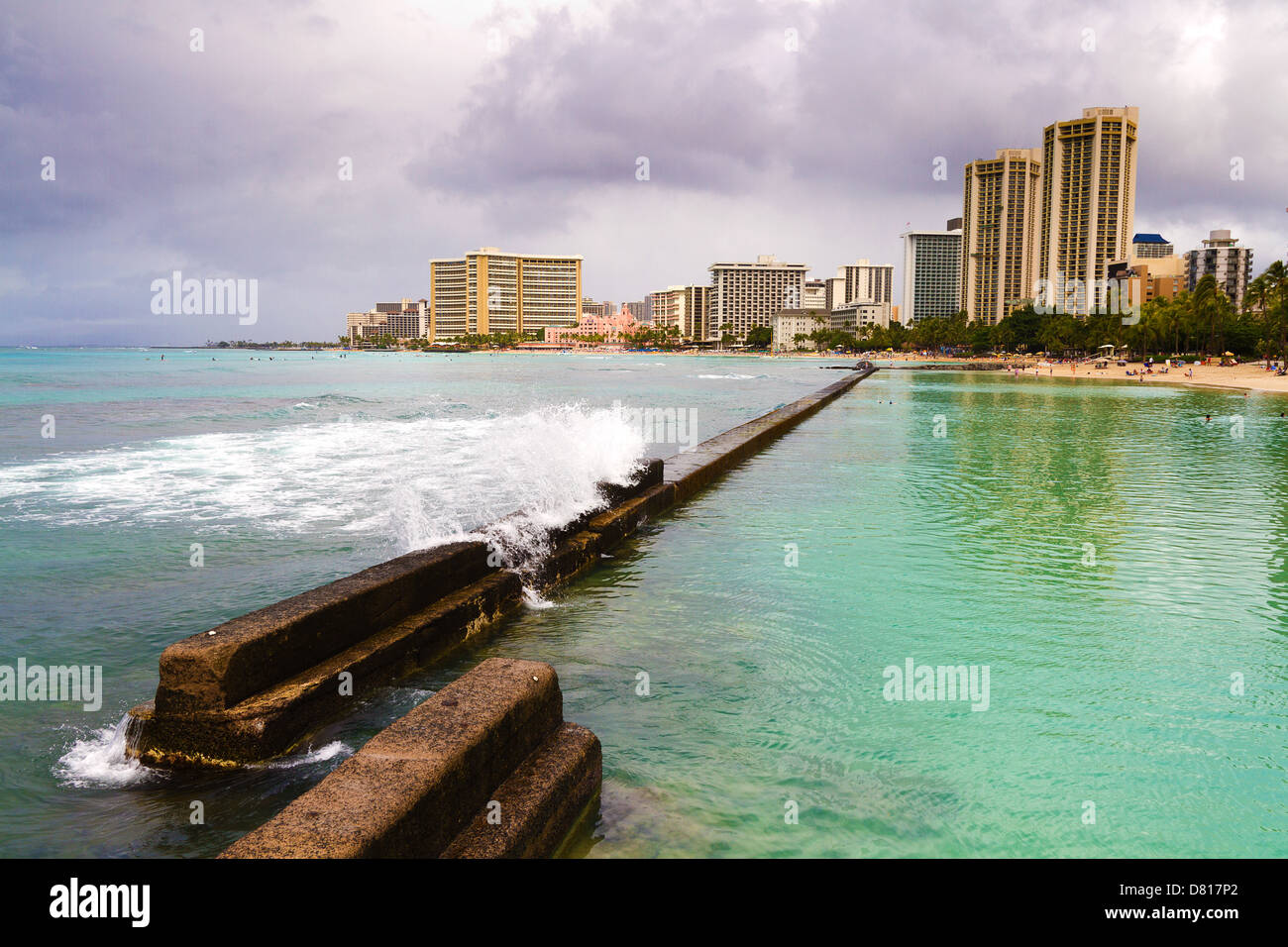 Ankommende Welle rauscht über Ufermauer am Kuhio Beach Park am Strand von Waikiki auf Oahu, Hawaii Stockfoto