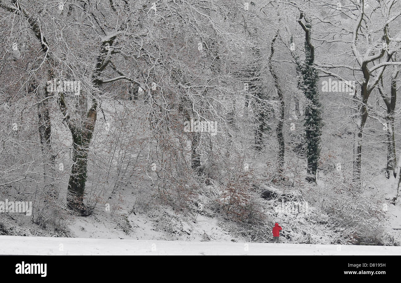 Ein Mann trägt einen roten Mantel geht durch Schnee in Pontypridd. Stockfoto
