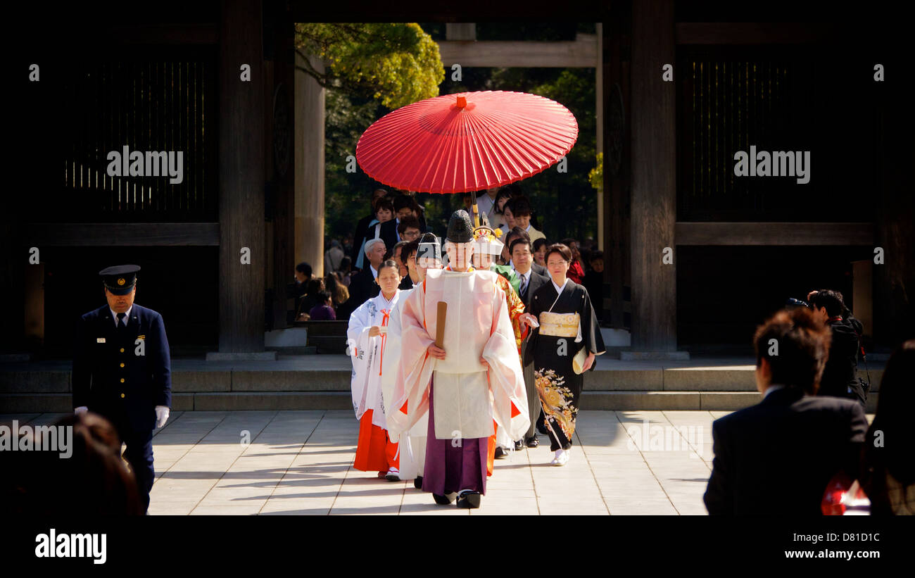 Japanische traditionelle Shinto Hochzeit im Meiji-Schrein mit Bright Red Gifu Regenschirm und Gefolge von Familie und Freunden Stockfoto