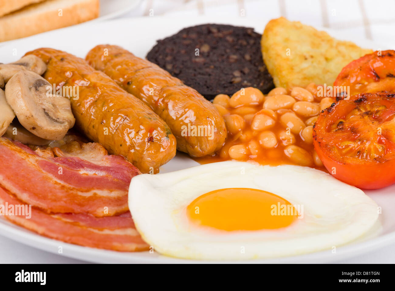 Full English Breakfast - Fry-up mit Ei, Speck, Champignons, Tomaten, Würstchen, Black Pudding, Rösti und gebackene Bohnen. Stockfoto