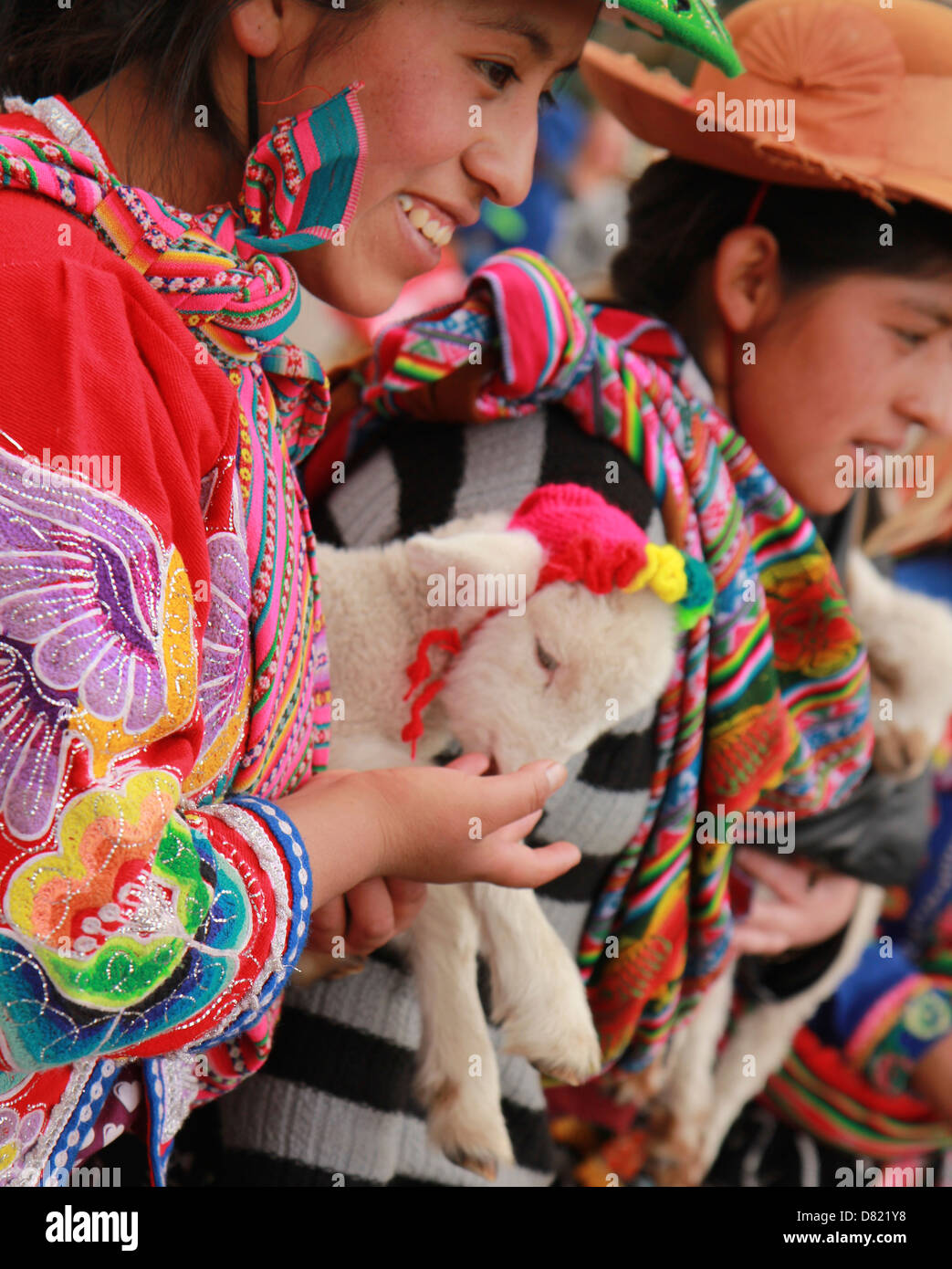 Mädchen in traditioneller Kleidung hält ein Baby Lamm. Plaza de Armas, Cuzco, Peru Stockfoto
