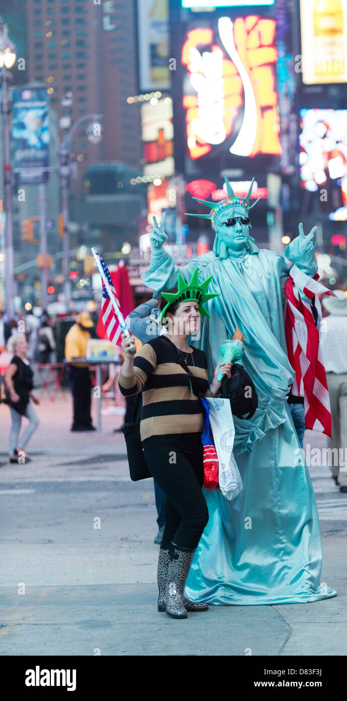 Ein Tourist auf dem Times Square hat ihr Foto mit einem Mann, gekleidet wie die Statue of Liberty. Stockfoto