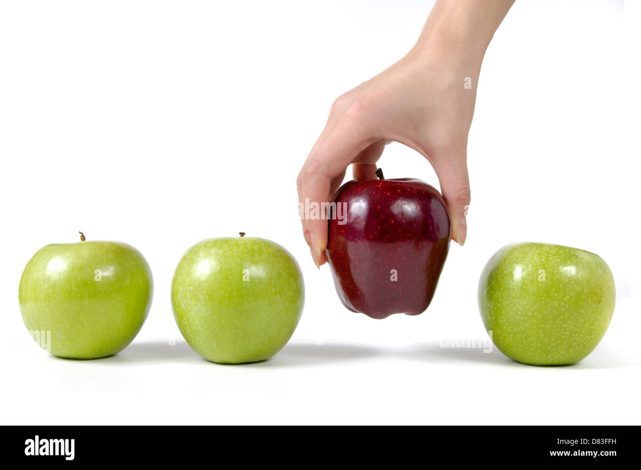 Person, die einen roten Apfel aus einer Reihe von grünen Äpfeln, Nahaufnahme einer Hand. Auswahl, Qualität, gesunde Ernährung Konzept. Isoliert Stockfoto
