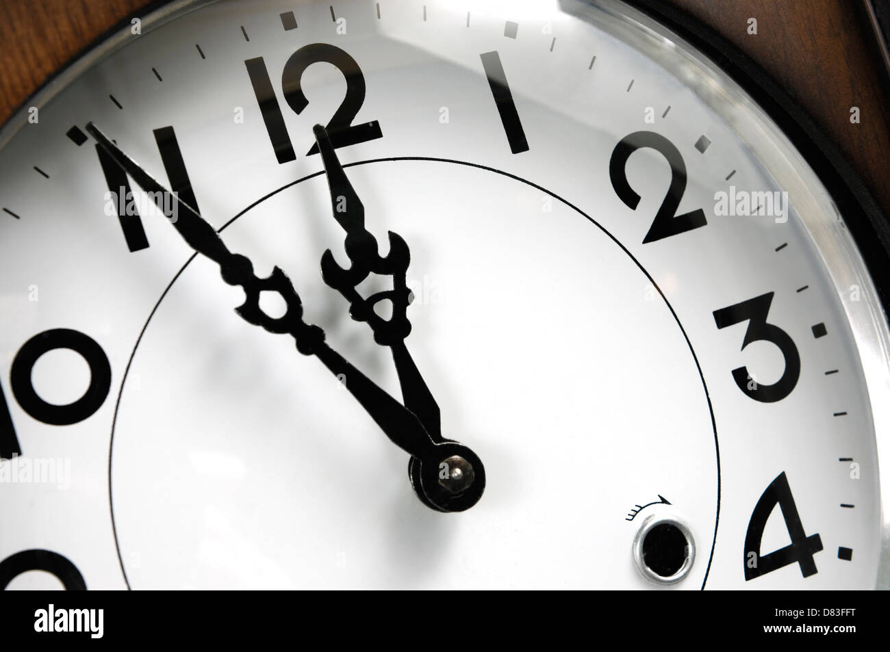 Wanduhr zeigt fünf Minuten bis zwölf Nahaufnahme eines Zifferblatts Stockfoto