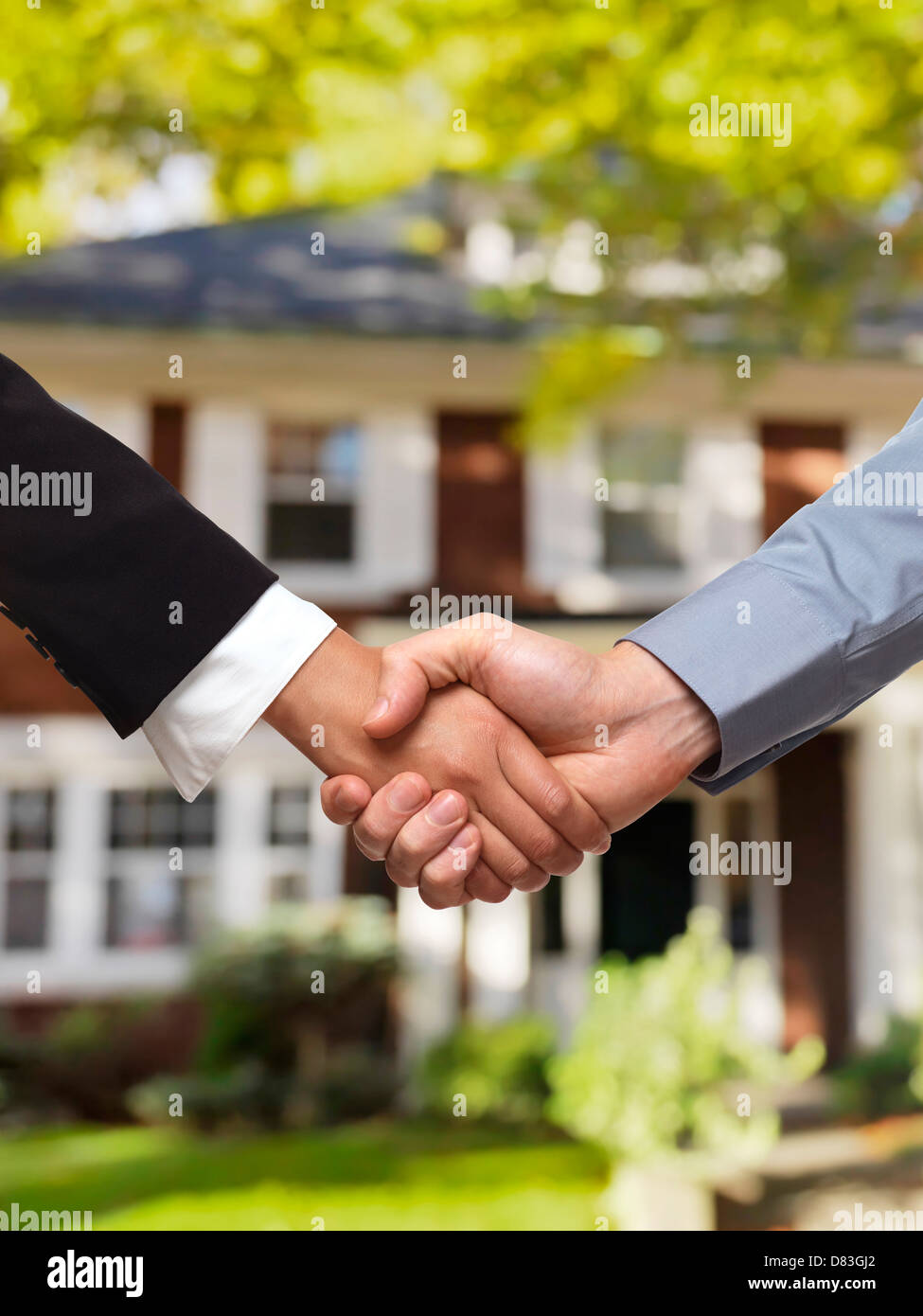 Mann und Frau, schütteln Hände vor einem Haus. Immobilien-Makler-Konzept. Stockfoto